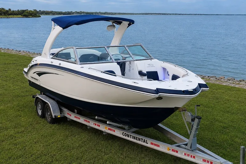 Slide: The Image of 2013 Chaparral 287 SSX boat on trailer by a lake, featuring sleek design and blue canopy. - 9