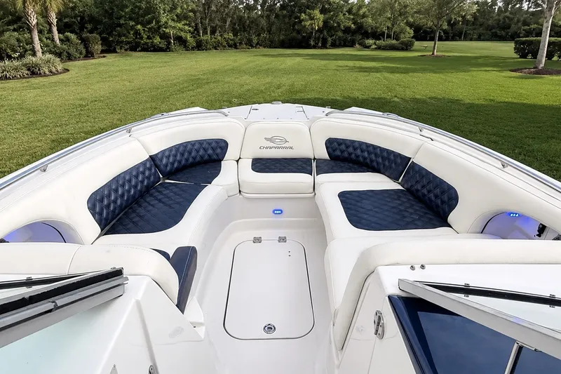 Slide: The Image of 2013 Chaparral 287 SSX boat interior with blue and white seating, surrounded by greenery. - 19
