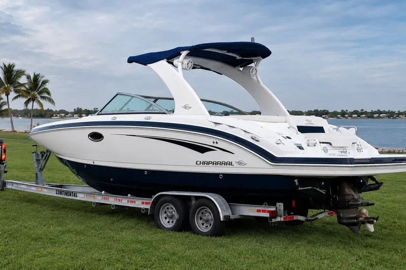 Slide: The Image of 2013 Chaparral 287 SSX boat on trailer by a lakeside with palm trees. - 1