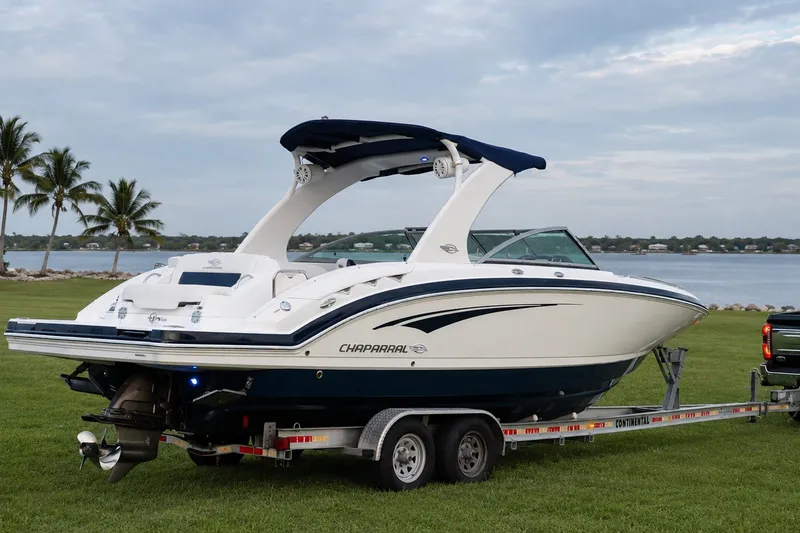 Slide: The Image of 2013 Chaparral 287 SSX boat on trailer by a lakeside with palm trees. - 7