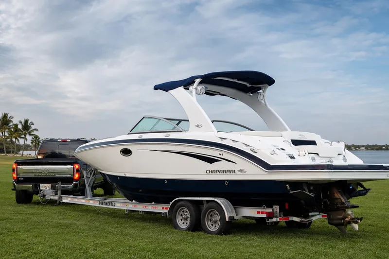 Slide: The Image of 2013 Chaparral 287 SSX boat on trailer, parked on grass near water. - 2