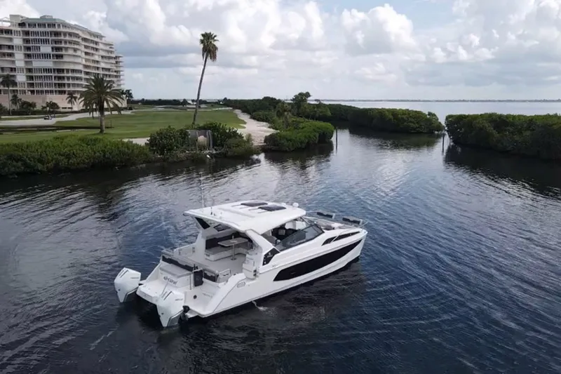 Slide: The Image of 2023 Aquila 36 Sport yacht cruising in a scenic coastal waterway. - 2