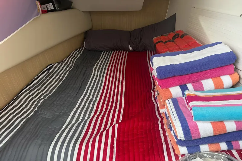 Slide: The Image of Cozy cabin interior of 2023 Aquila 36 Sport with striped bedding and colorful towels. - 24
