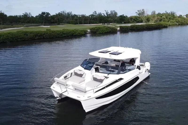 Slide: The Image of 2023 Aquila 36 Sport boat cruising on a calm river with lush greenery. - 3