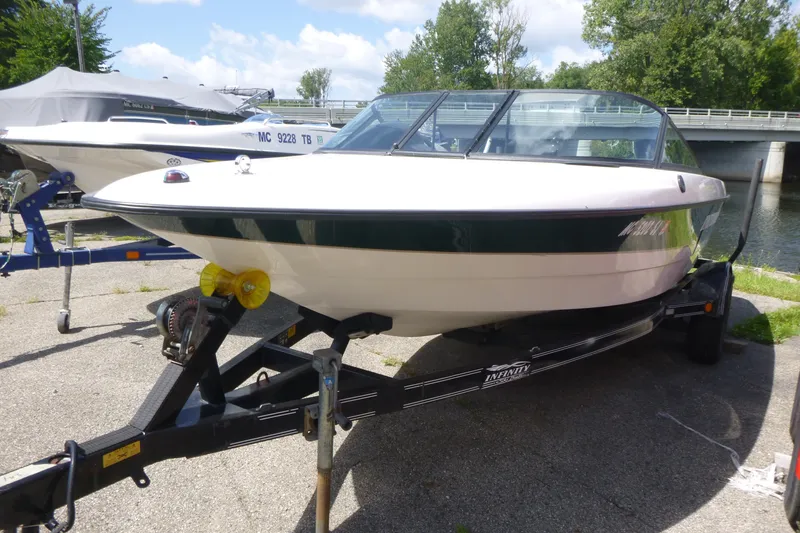 The Image of Infinity ZX-1 boat from 2001 on a trailer, parked near a river. - 1