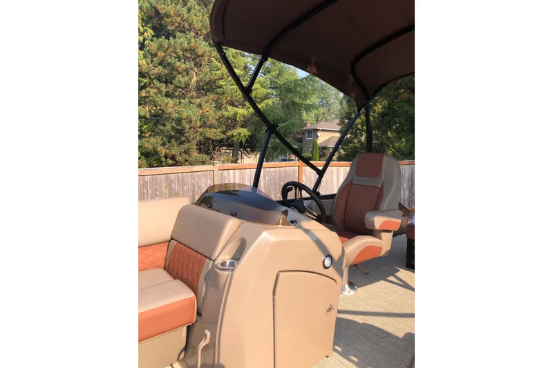 Slide: The Image of 2023 Bennington 22 LSB boat interior with tan and orange seating, steering wheel, and canopy. - 18