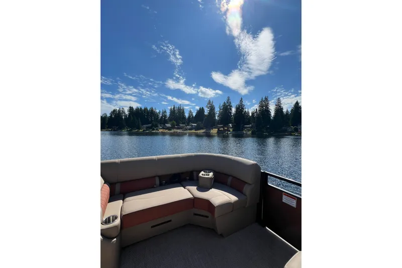 Slide: The Image of 2023 Bennington 22 LSB pontoon boat on a serene lake under a clear blue sky. - 19