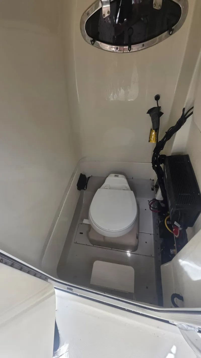 Slide: The Image of The image shows a compact boat toilet with a round window and some electrical connections. - 5