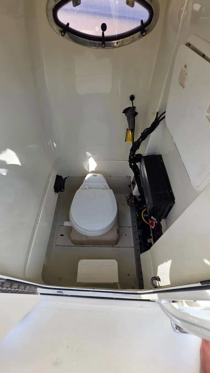 Slide: The Image of The image shows a clean, white boat toilet with a small window above. - 20