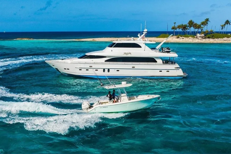 Slide: The Image of 2016 Cobia 237 Center Console boat cruising near a luxury yacht in tropical waters. - 5