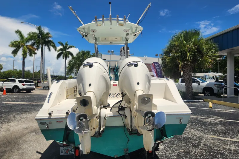 Slide: The Image of 2016 Cobia 237 Center Console boat with dual outboard motors, parked near palm trees. - 2