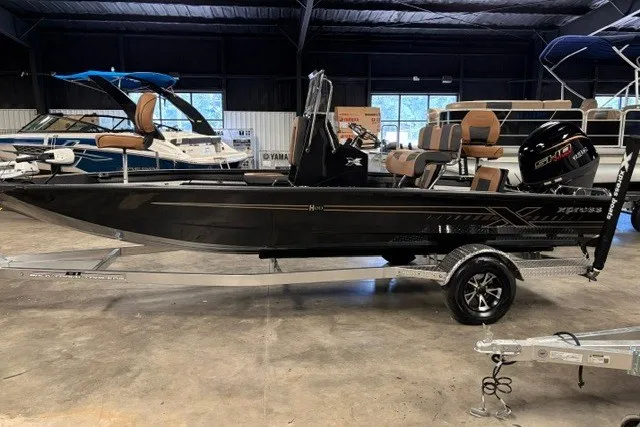Slide: The Image of 2027 Xpress H20 Bay boat in showroom, sleek black design, on trailer. - 2