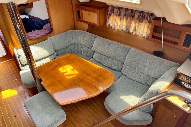 Slide: The Image of Cozy interior of 1999 Hunter Passage 420 yacht with plush seating and wooden table. - 24