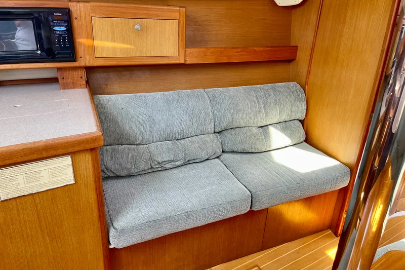Slide: The Image of Cozy interior of 1999 Hunter Passage 420 yacht with cushioned seating and wooden cabinetry. - 32
