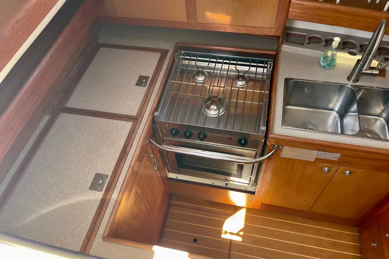 Slide: The Image of 1999 Hunter Passage 420 yacht kitchen with stove, sink, and wooden cabinetry. - 25