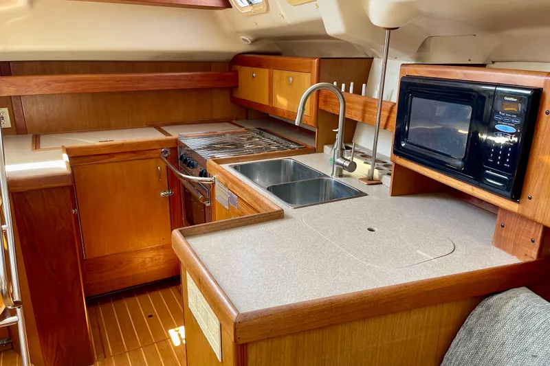Slide: The Image of 1999 Hunter Passage 420 yacht kitchen with wood cabinetry, stove, sink, and microwave. - 27
