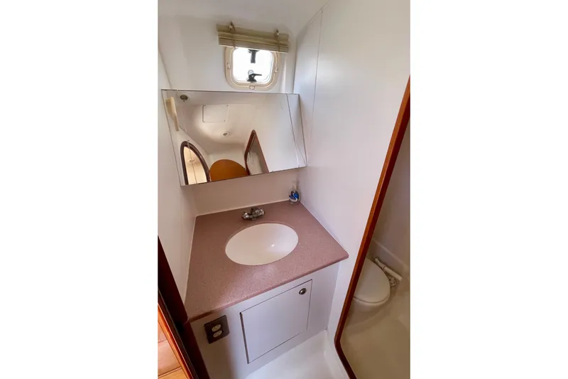 Slide: The Image of Bathroom interior of 1999 Hunter Passage 420 yacht with sink, mirror, and porthole window. - 43
