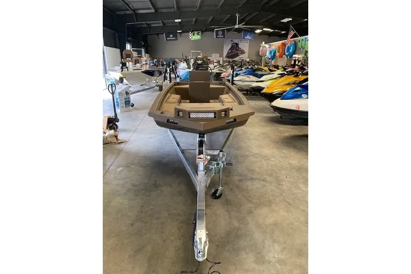 Slide: The Image of 2026 Xpress Bayou 180CC boat on trailer in showroom, surrounded by watercraft. - 3