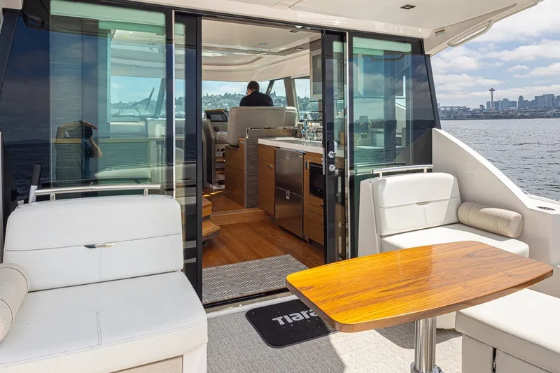 Slide: The Image of 2019 Tiara Yachts C44 Coupe interior with seating and table, overlooking water and cityscape. - 33