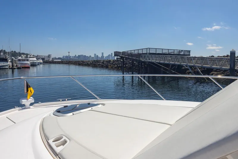Slide: The Image of 2019 Tiara Yachts C44 Coupe docked near a marina with city skyline view. - 58