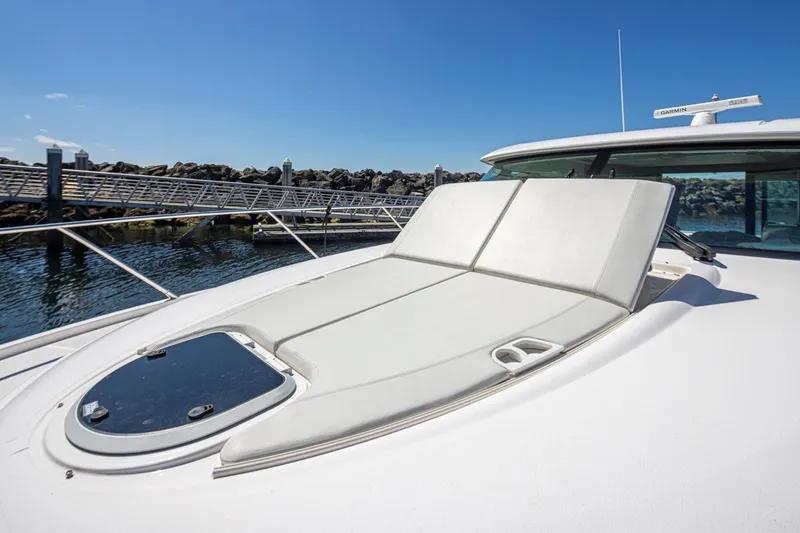 Slide: The Image of 2019 Tiara Yachts C44 Coupe with sunpad, docked at marina under clear blue sky. - 57