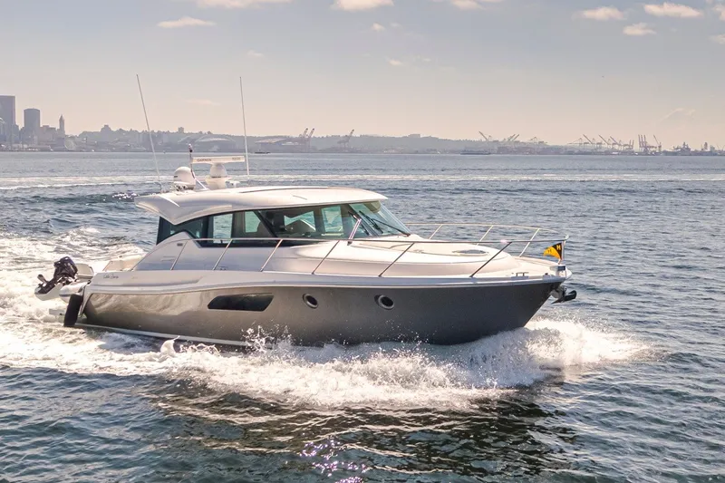 Slide: The Image of 2019 Tiara Yachts C44 Coupe cruising on open water with city skyline in background. - 51