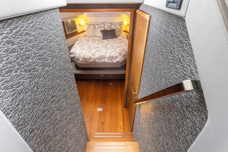 Slide: The Image of Interior of 2019 Tiara Yachts C44 Coupe, featuring a cozy bedroom with wooden flooring. - 15