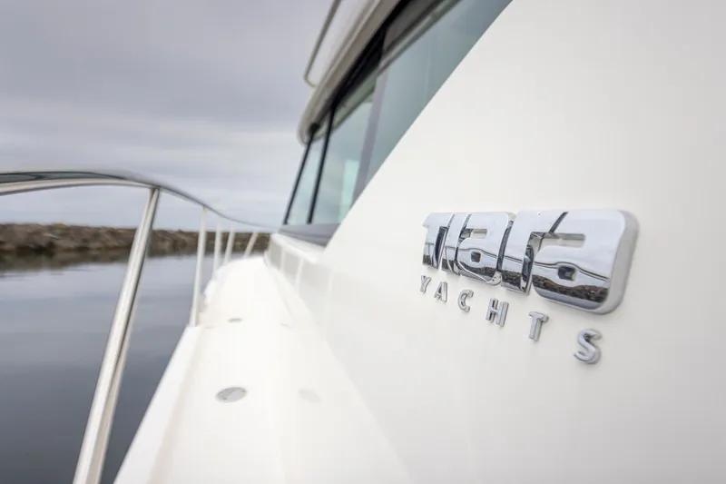 Slide: The Image of 2019 Tiara Yachts C44 Coupe side view with logo, docked on calm water. - 59