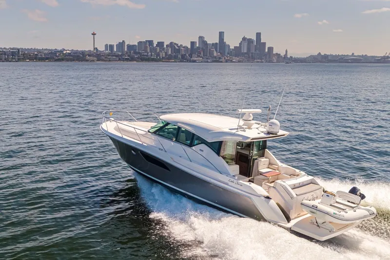 Slide: The Image of 2019 Tiara Yachts C44 Coupe cruising on water with city skyline backdrop. - 49