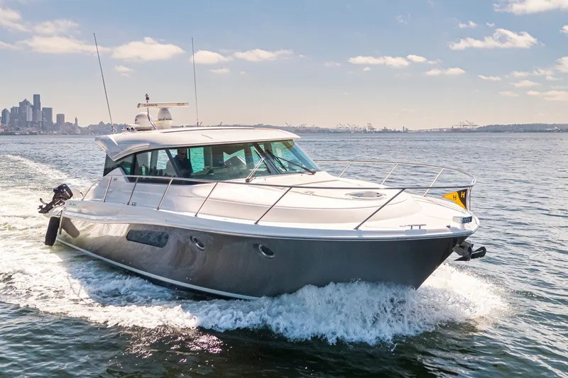 Slide: The Image of 2019 Tiara Yachts C44 Coupe cruising on open water with city skyline backdrop. - 53
