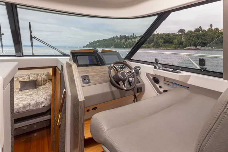 Slide: The Image of 2019 Tiara Yachts C44 Coupe interior with helm, luxurious cabin, and scenic water view. - 12