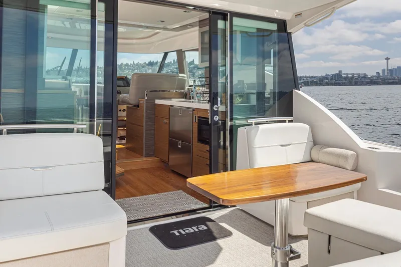 Slide: The Image of 2019 Tiara Yachts C44 Coupe interior with seating and table, overlooking water and cityscape. - 35
