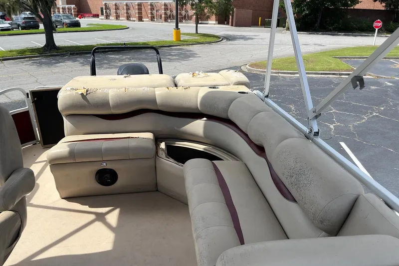 Slide: The Image of 2014 Bentley Pontoons Elite 250 interior with worn beige seating in a parking lot. - 8