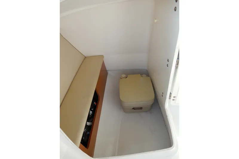 Slide: The Image of 2017 Chaparral 246 SSi boat interior with portable toilet and cushioned seating. - 20