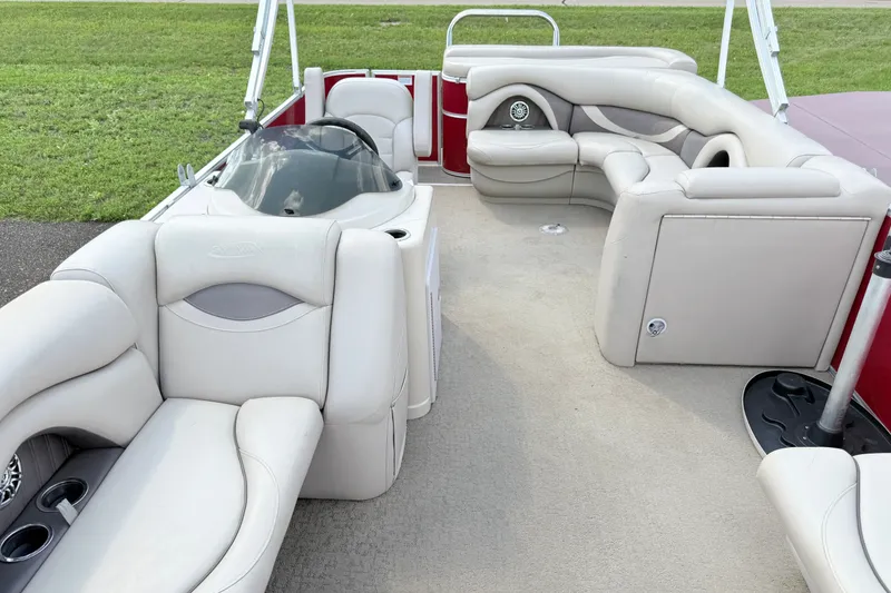 Slide: The Image of 2016 Sylvan Mirage 8520 pontoon boat interior with plush seating and helm, parked on grass. - 7