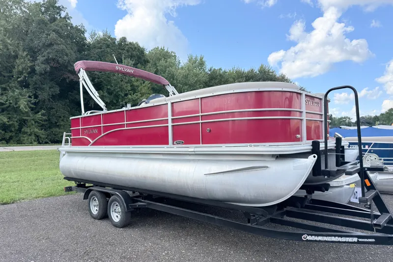 Slide: The Image of 2016 Sylvan Mirage 8520 pontoon boat on trailer, parked outdoors under a blue sky. - 1