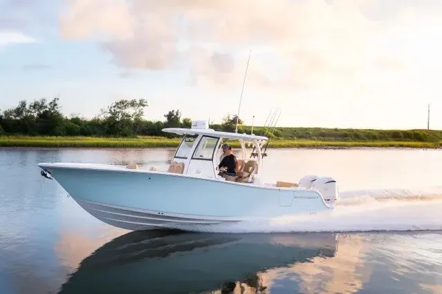 The Image of 2027 Sportsman Open 282 Center Console boat cruising on calm water at sunset. - 1