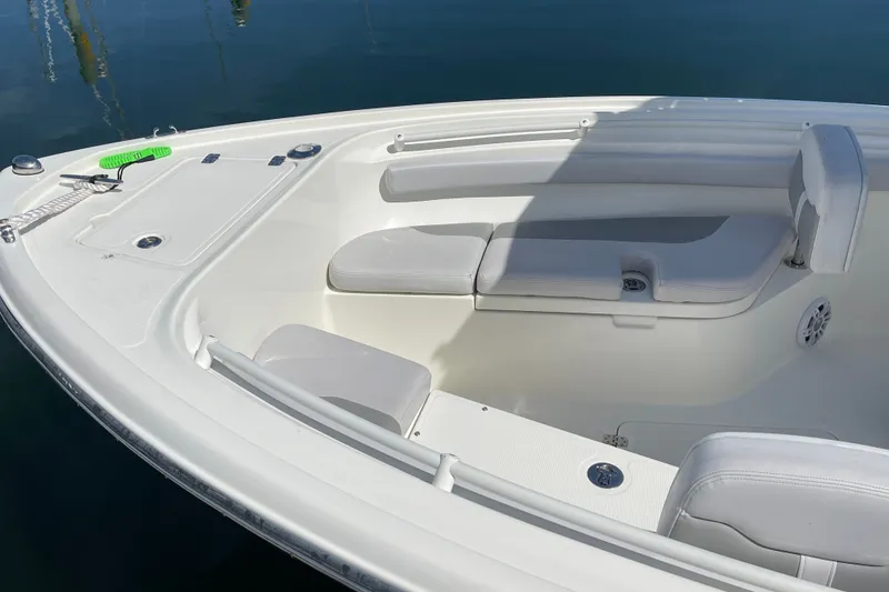 Slide: The Image of 2023 Mako 214 Center Console boat with cushioned seating, docked on calm water. - 20