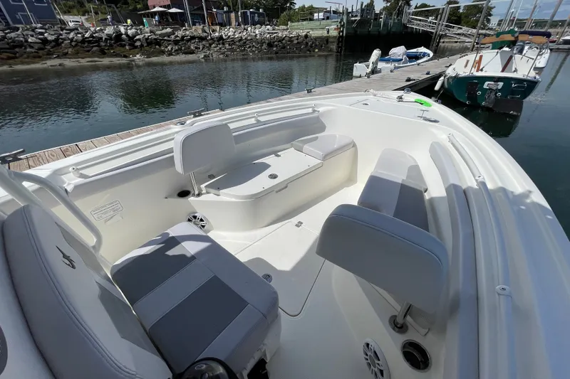 Slide: The Image of 2023 Mako 214 Center Console boat interior at dock, featuring seating and storage. - 35