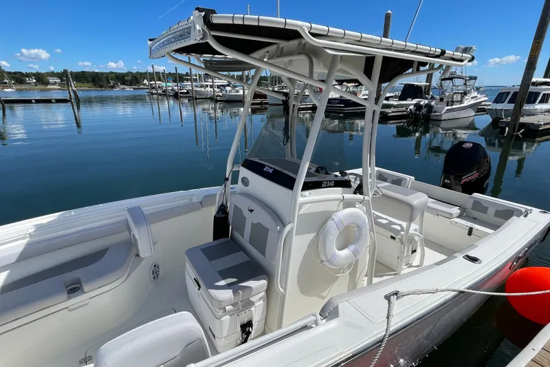 Slide: The Image of 2023 Mako 214 Center Console boat docked in a marina under clear blue skies. - 22