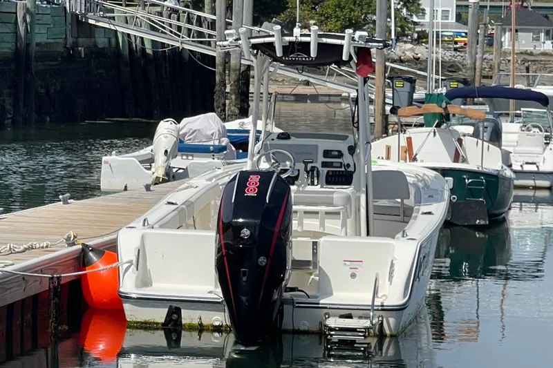 Slide: The Image of 2023 Mako 214 Center Console boat docked at marina, featuring sleek design and powerful engine. - 24
