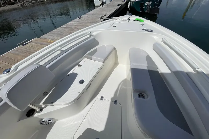 Slide: The Image of 2023 Mako 214 Center Console boat interior with seating and storage, docked by the water. - 36
