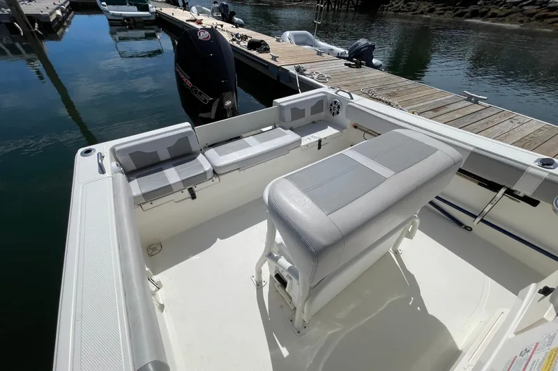 Slide: The Image of 2023 Mako 214 Center Console boat interior at dock, featuring seating and outboard motor. - 32