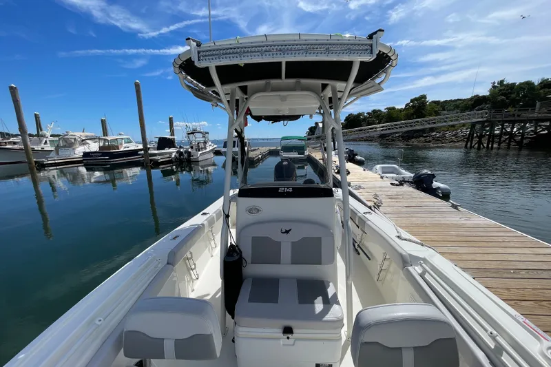 Slide: The Image of 2023 Mako 214 Center Console boat docked at a marina under clear blue skies. - 38