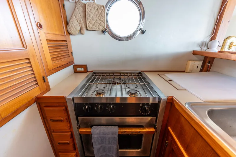 Slide: The Image of 1991 Kadey-Krogen 42 yacht kitchen with stove, wooden cabinets, and porthole window. - 55