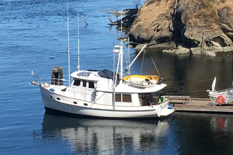 Slide: The Image of Kadey-Krogen 42 yacht from 1991 docked by rocky shoreline. - 1
