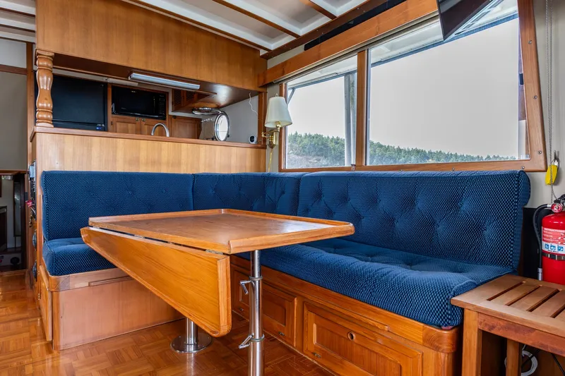 Slide: The Image of Interior of 1991 Kadey-Krogen 42 yacht with blue cushioned seating and wooden table. - 28