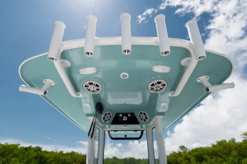 Slide: The Image of 2027 Sportsman Masters 247OE Bay Boat T-top with rod holders and speakers under blue sky. - 3