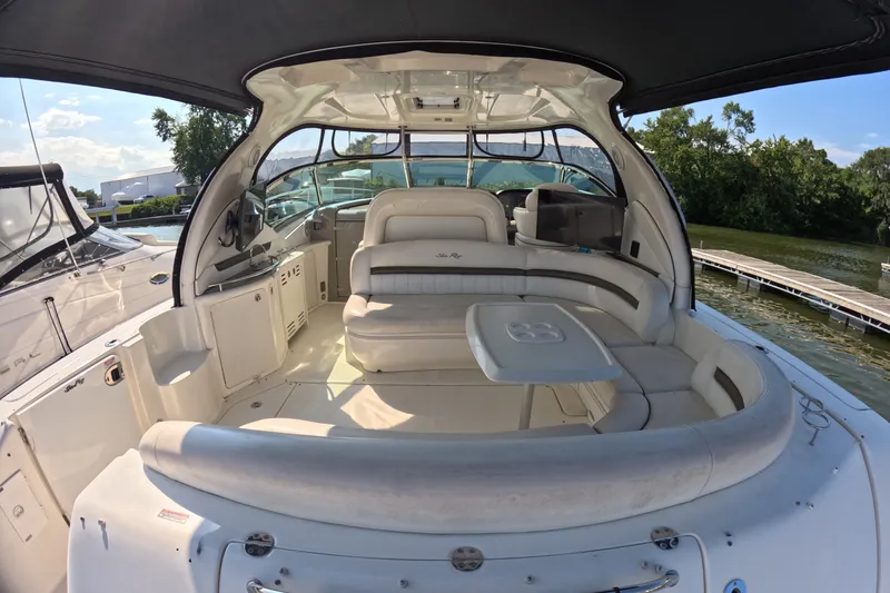 Slide: The Image of 2007 Sea Ray 44 Sundancer yacht interior with spacious seating and table, docked by lush greenery. - 25