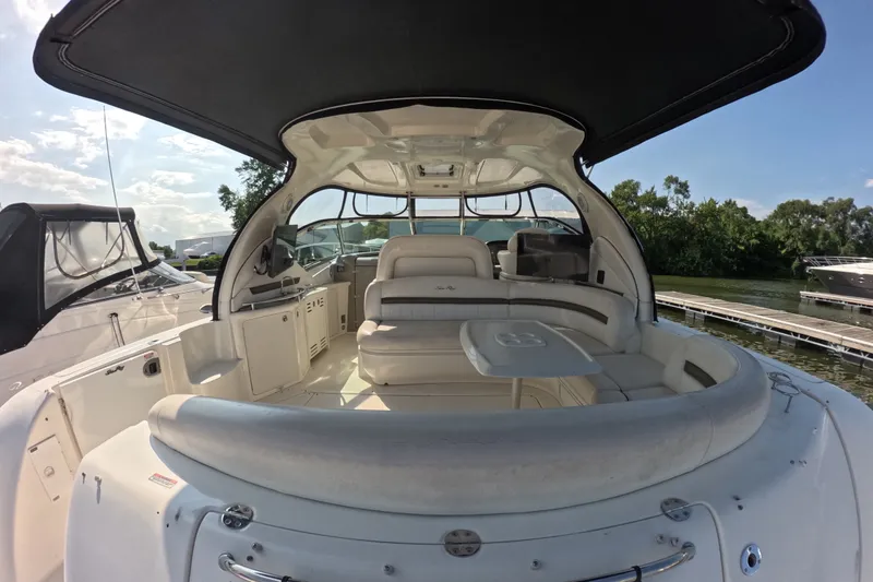 Slide: The Image of 2007 Sea Ray 44 Sundancer yacht interior with seating and table, docked by lush greenery. - 5